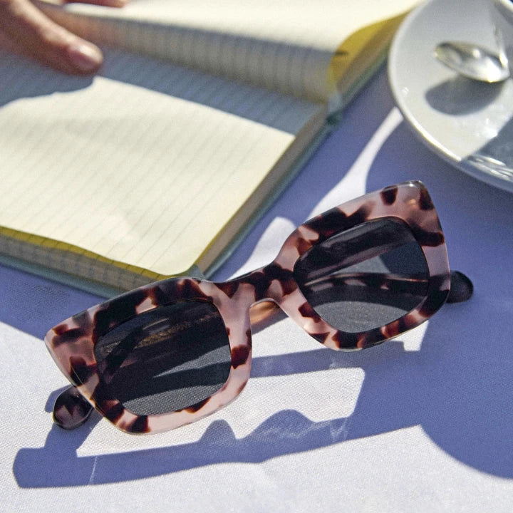 Pink tortoise sunglasses on a table beside a notebook: a Vicci Eyewear Black Friday 2025 pick.